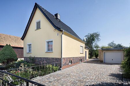 Pastellgelbes Einfamilienhaus mit spitzem Satteldach und frischer Fassaden