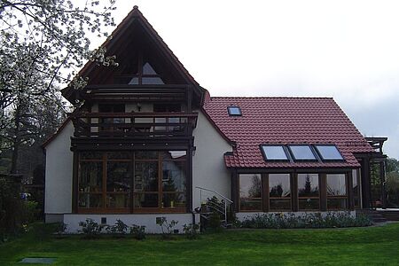 Weißes Wohnhaus im Grünen mit leicht ergrauter Fassadenbeschichtung