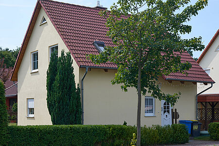 Pastellgelbes Einfamilienhaus nach der Sanierung mit Spezialputzfassade