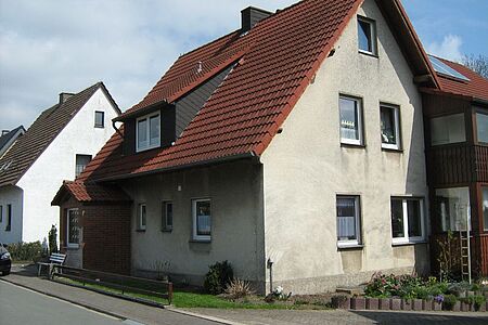 Verputztes Wohnhaus mit unebenmäßiger, sanierungsbedürftiger Fassade