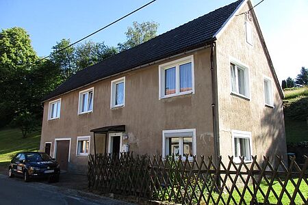 Beige verputztes Wohnhaus vor der Fassadensanierung