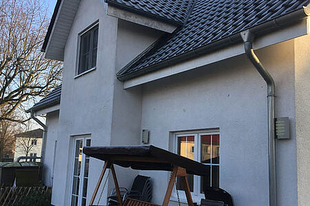 Weißes Einfamilienhaus mit stark verwitterter Fassade