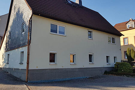 Großes Wohnhaus mit zum Teil vertäfelter Fassade vor der Sanierung