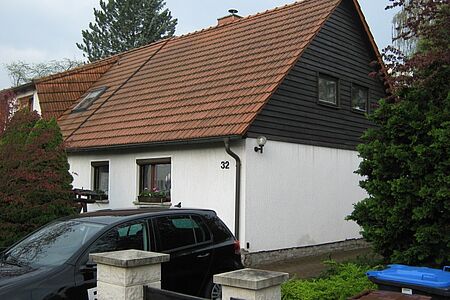 Einfamilienhaus mit sichtbaren Wasserschäden an der Fassade im Erdgeschoss