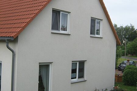 Einfamilienhaus mit alter Fassade in schmutzigem Weiß
