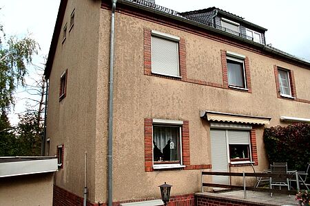 Haus mit sichtbaren Witterungsschäden an der Fassade und kleinem Balkon