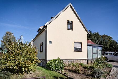 Einfamilienhaus mit Wintergarten und frischer Fassade in sehr hellem Pastellorange