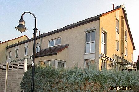 Reihenhaus mit sanierungswürdiger Fassade in verschmutztem Pastellorange