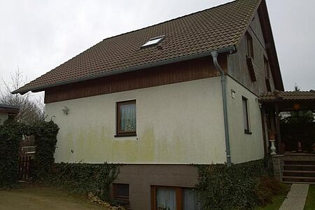 Weißes Wohnhaus mit Grünspann auf der Fassade