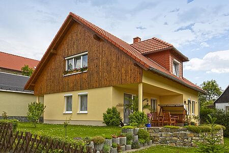 Einfamilienhaus mit gelber Fassade und Holzvertäfelung