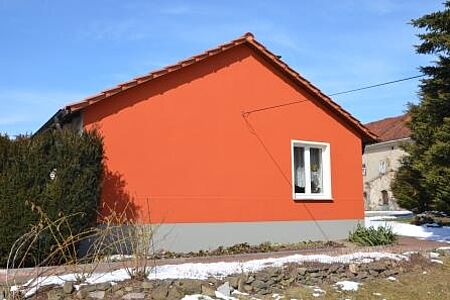 Bungalow mit flachem Satteldach und knallroter Fassade