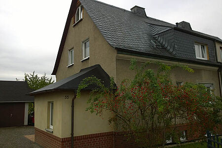 Doppelhaushälfte mit moosgrüner, verschmutzter Fassade