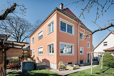Orangefarbene Villa mit großen Fenster nach der Rundum-Sanierung