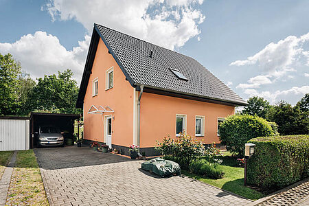 Einfamilienhaus mit Satteldach und frischer Fassade in strahlendem Apricot