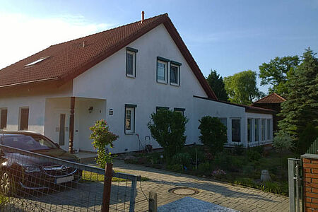Großes, weißes Wohnhaus mit leicht verschmutzter Fassade