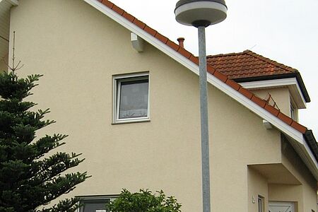 Vorher	Einfamilienhaus mit schiefem Dach und hellgelber Fassade