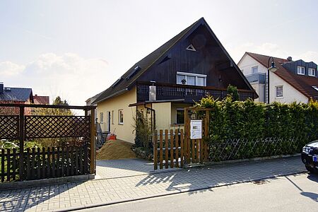 Einfamilienhaus mit frischer, pastellgelber Fassade und dunkelbrauner Vertäfelung im Obergeschoss 
