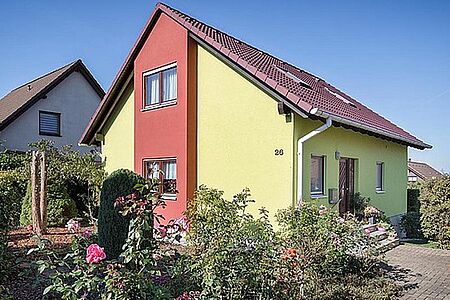 Grünes Wohnhaus mit roten Elementen auf der Fassade