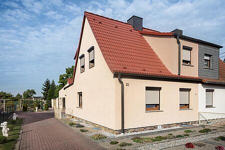 Doppelhaus mit pastelloranger sowie weißer und grauer Fassade