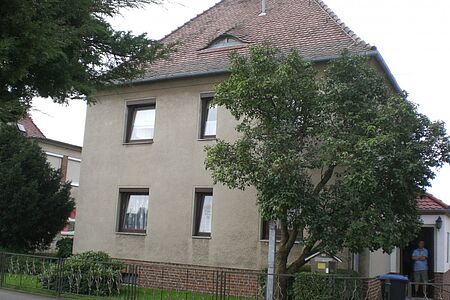 Mehrfamilienhaus mit grauer, sanierungsbedürftiger Fassade