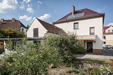 Weißes Wohnhaus mit Walmdach und Markise