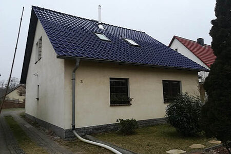 Kleines Einfamilienhaus mit verwitterter, weißer Fassade
