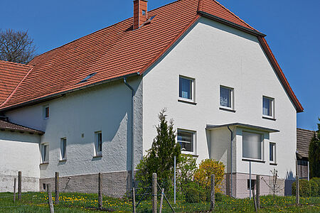Großes Wohnhaus mit rotem Krüppelwalmdach und frischer pastellblauer Fassade