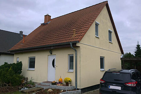 Gelbes Einfamilienhaus mit stark verschmutzter Fassade 