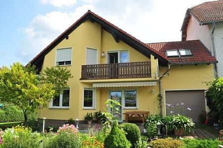 Gelbes Haus mit Balkon nach der Fassadensanierung