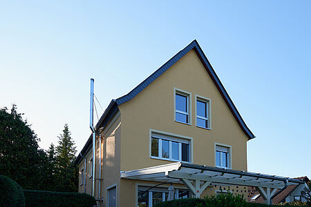 Großes Wohnhaus mit sonnig-gelber Fassade und angebautem Überbau für die Terrasse