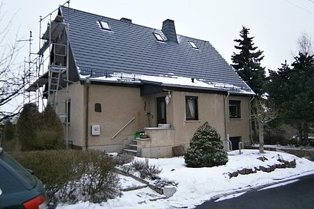 Verschneites Einfamilienhaus mit Baugeländer an der Seite