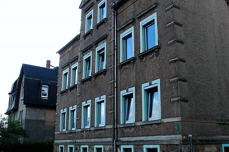 Altes Gebäude mit einigen Fassadenschäden, insbesondere unterhalb der verschiedenen Fenster