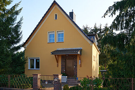 Einfamilienhaus mit orange-gelber Fassade nach der Sanierung