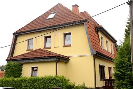 Großes Wohnhaus mit Krüppelwalmdach und dottergelber Fassade