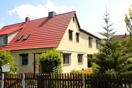 Helles Einfamilienhaus mit kleinem Garten und Holzzaun im Vordergrund