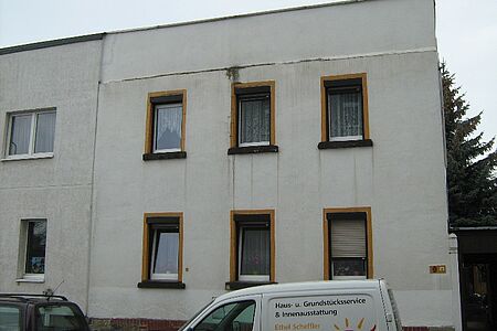 Weißes Haus mit Flachdach und alter Fassade