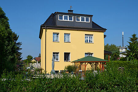 Dreistöckige Villa mit Klimaschutzfassade in sonnigem Gelb