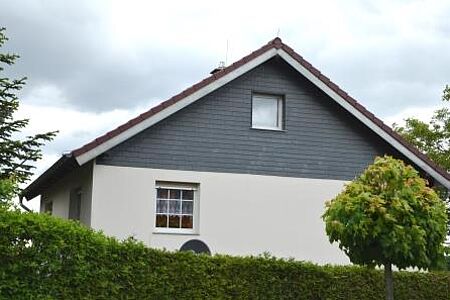Haus mit sauberer, weißer Fassade und Vertäfelung in Grau