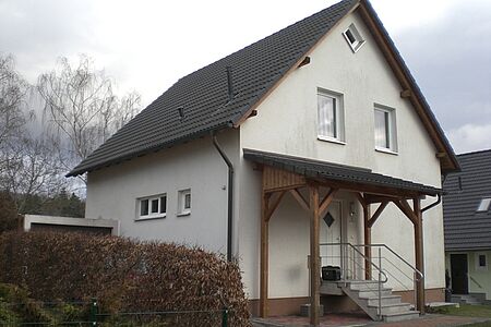 Weißes Haus mit Satteldach und Holzveranda
