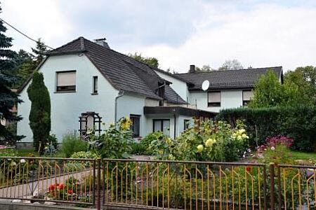 Großes Haus mit hellblauer Fassade und gepflegtem, großen Garten 