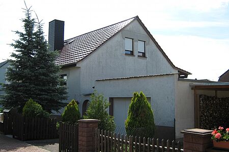Weiß verputztes Haus mit dreckiger Fassade vor der Sanierung