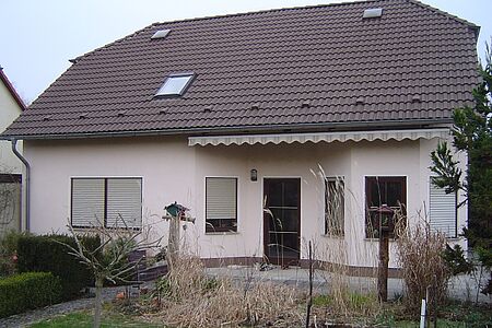Wohnhaus mit Krüppelwalmdach und rosaner Fassade