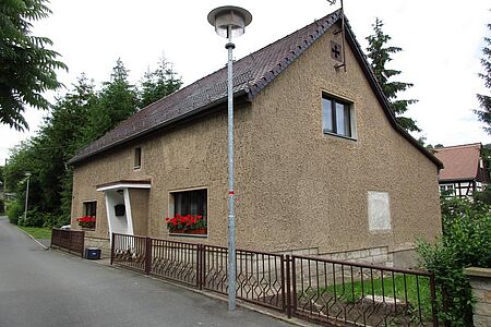 Graubraun verputztes Wohnhaus mit Treppenaufgang ohne Geländer