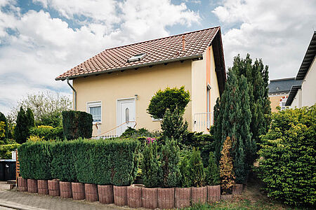 Einfamilienhaus mit frischer Fassade in hellem Orange und Garten