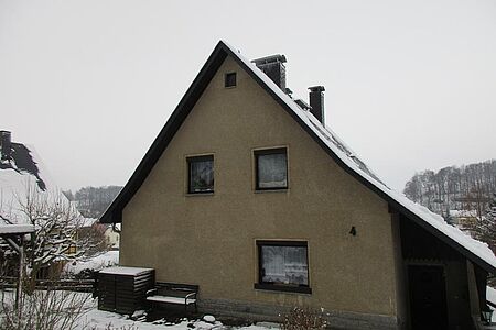 Braun verputztes Wohnhaus mit überdachtem Eingangsbereich