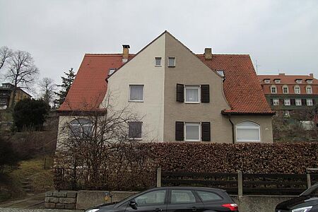 Doppelhaus mit einer hellgelben Hälfte und einer braun verputzten Hälfte