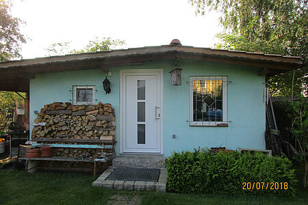 Bungalow mit sehr flachem Satteldach und türkiser Fassade