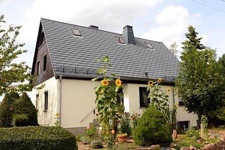 Weiß-sanierte Fassade eines Einfamilienhauses mit buntem Vorgarten