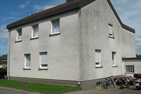Grau verputztes Mehrfamilienhaus vor der Fassadensanierung