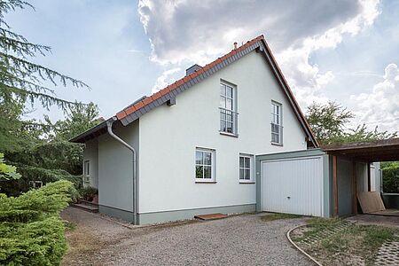 Kleines Wohnhaus mit sehr heller, pastell-türkiser Fassade und Garage